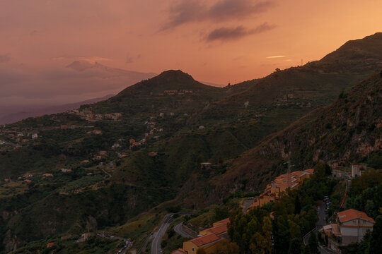 Majestic sunset view over a hillside village with the distant Mount Etna volcano in Sicily