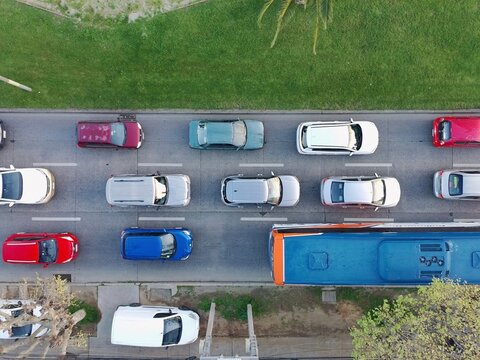 Top down drone view of cars and a public bus traveling along a congested multilane urban road.