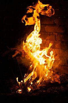 Irregular flames appear to dance as hot gases expand and react with the surrounding air. A rustic style fireplace at night creates a striking contrast with the dark surroundings.