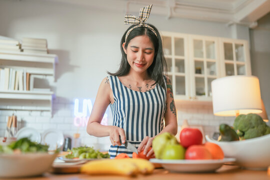 A content creator smiles while preparing colorful vegetables during a cooking livestream, capturing modern food influencer culture at home.