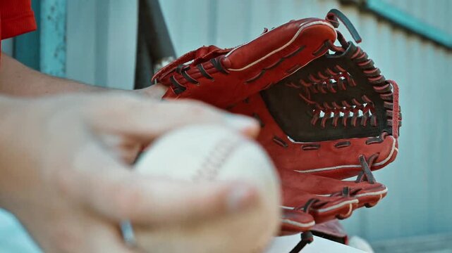 Professional Close-up of a Worn Baseball Resting in a Red Leather Glove Held by a Player in a Stadium Dugout