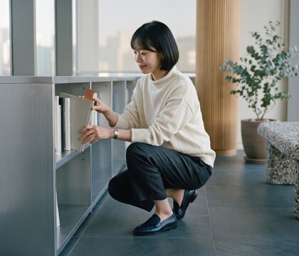 Generative AI, Young Asian woman organizing books on a modern office shelf