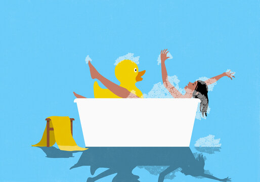 Carefree woman playing in bubble bath with oversized rubber duck against blue background