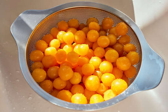 Close up of fresh, wet yellow Mirabelle plums in colander