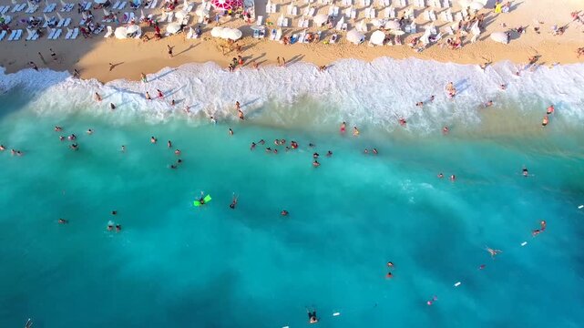 Aerial Kaputas Beach in Kas Antalya Turkey shows turquoise water, cliffs, umbrellas, and crowds.