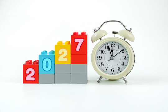 Colorful 2027 number blocks arranged beside an alarm clock representing New Year countdown, time passing, deadlines and a fresh start.