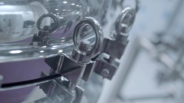 The lid of the chemical reactor, made of stainless steel, is securely closed with multiple clamps. Closeup. Shot in motion