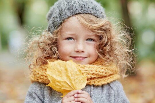 Happy child holding yellow autumn leaf outdoors