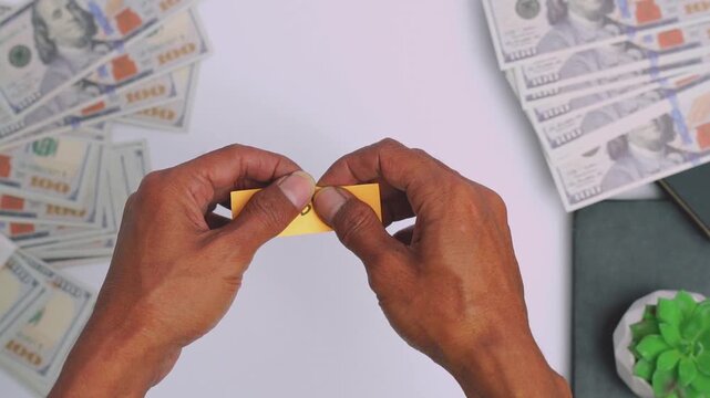 Close up of a hands tearing apart a yellow sticky note with PROBLEM word written on it surrounded by money bills on a table.