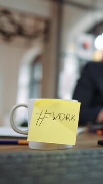 Yellow sticky note with inscription work on coffee cup in office, vertical video. Focus on career and job, working day in big international corporation, inside boardroom of modern company, business
