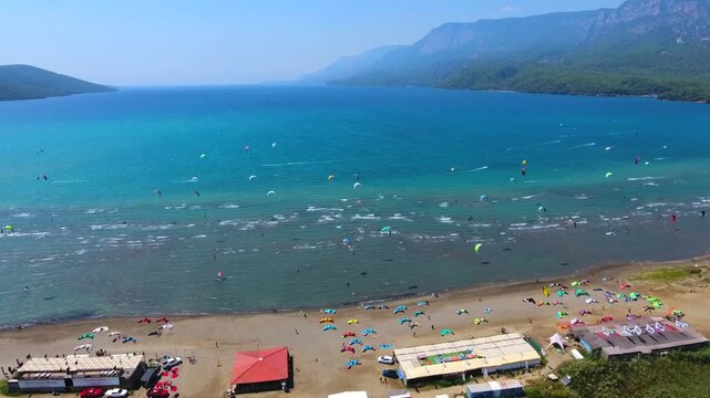 Aerial drone view of kiteboarders in Akyaka Gokova Bay Turkey with wind, waves, and beach.