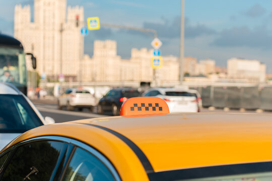Yellow taxi with a checkered sign on a busy city street