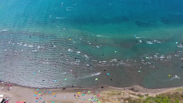 Aerial drone view of kiteboarders in Akyaka Gokova Bay Turkey with wind, waves, and beach.
