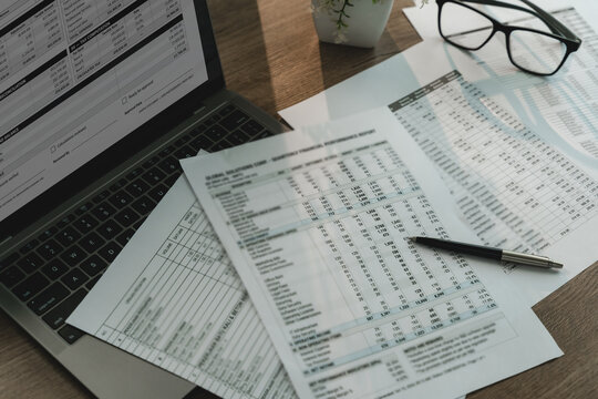 Accounting spreadsheets and financial reports beside laptop, calculator and pen, showing financial calculation, data review and business analysis workflow.