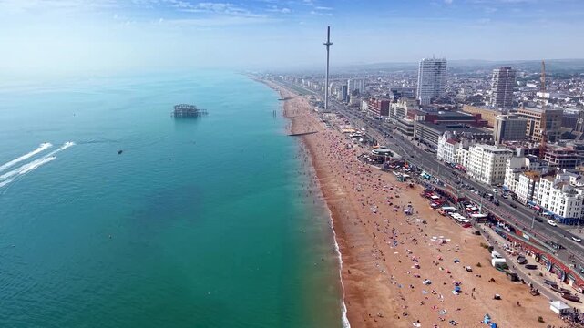 Establishing aerial view of the cityscape of Brighton, England, with beachfront and old, burned West Pier during a sunny day