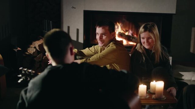 People Gather by Fireplace in Warm Candlelight