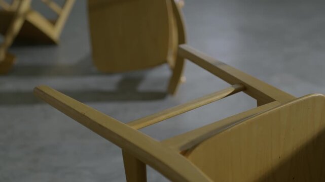 Close up of an overturned wooden chair on a cold concrete floor symbolizing failure and disorder