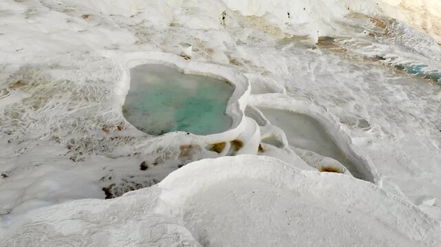 Aerial drone view of Pamukkale travertine pools in Denizli Turkey with white limestone bowls.