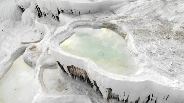 Aerial drone view of Pamukkale travertine pools in Denizli Turkey with white limestone bowls.