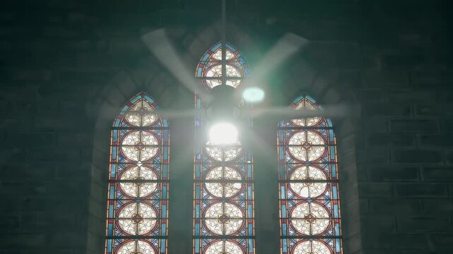 A beautiful intricate ornate stained-glass windows inside the Christ the King Cathedral (also known as the Stone Church or Nha tho Nui) in Nha Trang, Vietnam, partially obscured by a rotating ceiling 