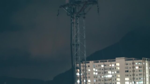 A tall telecommunication tower with steel lattice framework typically used for cellular or wireless communication signals with mounted antennas and a flashing red warning light at the top 