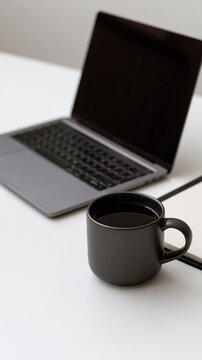 Modern laptop and black coffee mug on a white desk with copy space for business