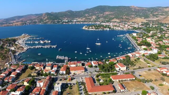 Aerial drone view of Foca harbor in Izmir Turkey with marina, boats, houses, and Aegean bay.