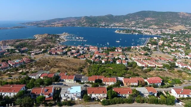 Aerial drone view of Foca harbor in Izmir Turkey with marina, boats, houses, and Aegean bay.