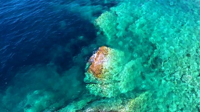 Aerial drone overhead of submerged rock and seamount in Chile with shallow turquoise water.