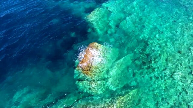 Aerial drone overhead of submerged rock and seamount in Chile with shallow turquoise water.
