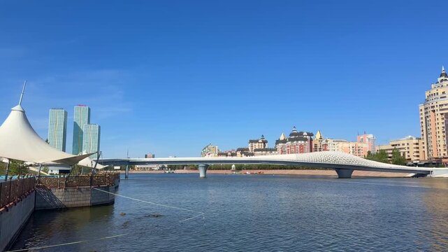 Urban river scenery in Astana, featuring modern architecture, pedestrian infrastructure and reflective water within capital city landscape, Kazakhstan, shot handheld, 4k 