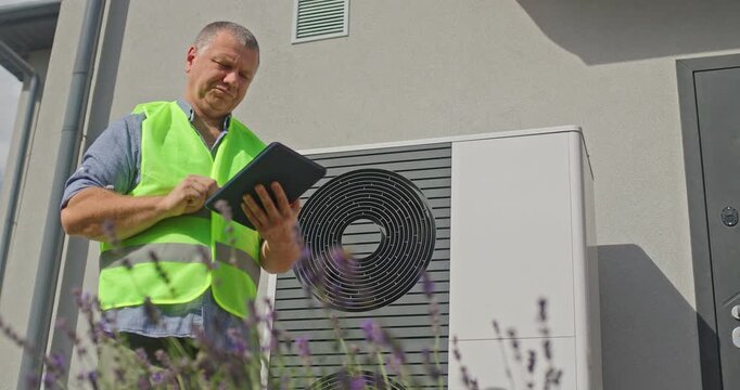 Technician Inspects Outdoor Heat Pump with Tablet