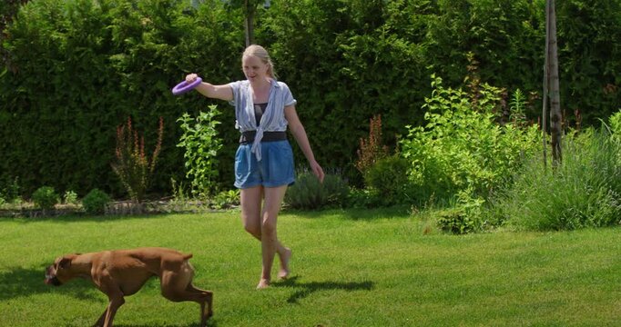 Woman Walking Across Sunny Garden Lawn with Dog