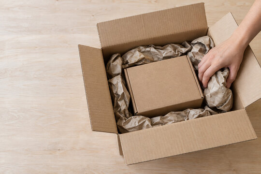 Hand adding packing paper around a box inside a carton