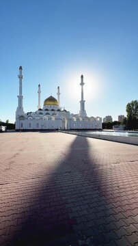 Abu Nasr Al-Farabi Mosque featuring golden dome, four tall minarets, white Islamic architecture and spacious paved square, Astana, Kazakhstan, shot handheld, vertical video, 4k footage