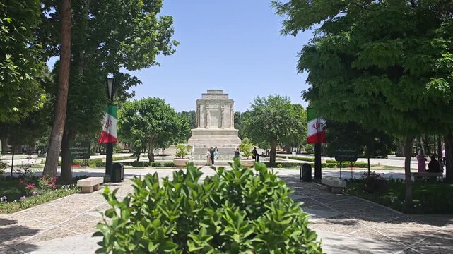 Visitors and Iranian flags appear around Ferdowsi Tomb in a bright cultural heritage scene.