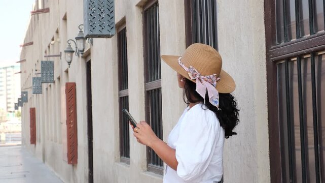 Tourist woman checking maps navigation in smartphone beside traditional stone house in Al Fahidi heritage district during Old Dubai travel