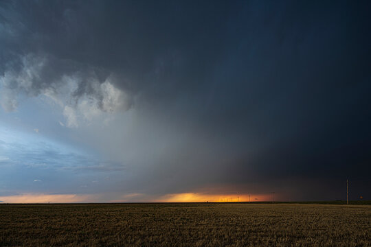 Storm clouds gather over field at sunset in ulysses, kansas
