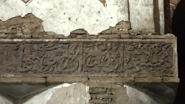 Worn inscriptions and wall ornament survive inside Nizam al Mulk Dome in Iran.