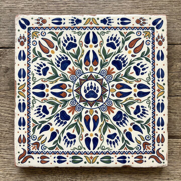 Square ceramic decorative tile featuring intricate colorful animal paw print patterns and floral elements