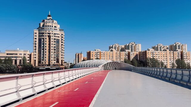 Atyrau Bridge in Astana, capturing sweeping white arches, intricate canopy, red walking lane and contemporary urban architecture, Kazakhstan, shot handheld, 4k footage