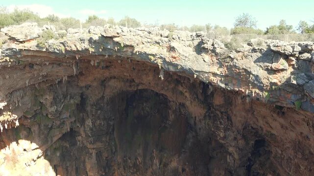 Rock soil layers line cave wall with stalactites, sediment bands underground geology detail.