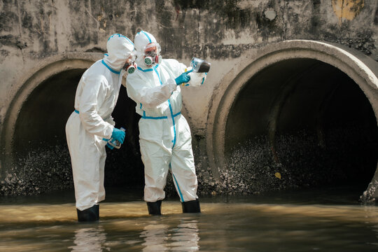 Environmental workers inspect a collected wastewater sample near an outfall during water quality monitoring and pollution investigation.