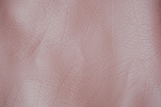 Detailed abstract background featuring soft pinkish brown faux leather material with natural creases