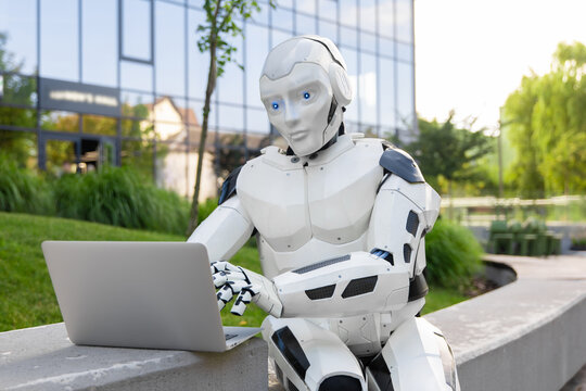 Humanoid android using silver laptop computer