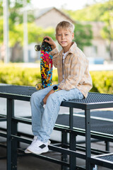Cute blonde boy with a skateboard looking contented and enjoyed © zinkevych
