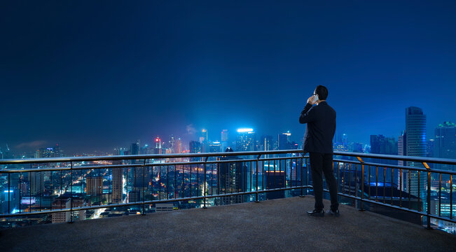 Businessman talking on phone overlooking city at night