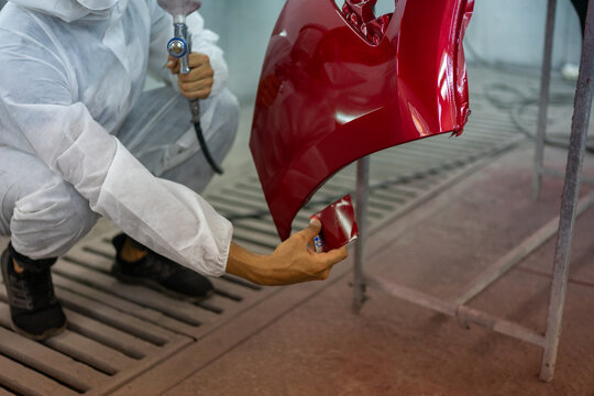 Mechanic Kneeling to Compare Paint Sample on Car Hood