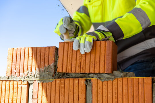 Construction worker laying red brick using trowel and mortar