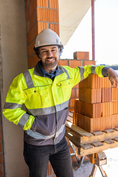 Construction worker leaning against stack of bricks